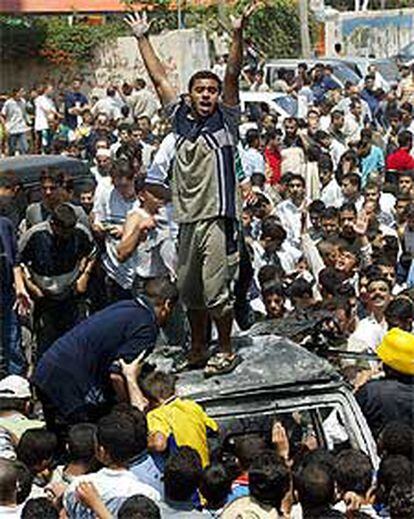 Cientos de palestinos protestan junto al auto destrozado de Rantisi.