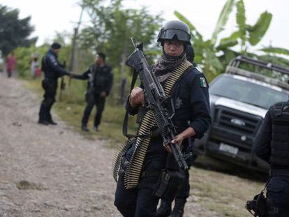 Un polic&iacute;a mexicano vigila los alrededores de las fosas halladas en Iguala.