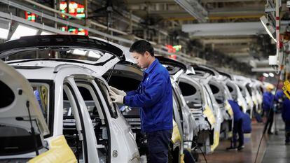 Varios trabajadores ensamblan distintas partes de coches eléctricos en la fábrica de General Motors en Liuzhou, en China, en febrero de 2019.