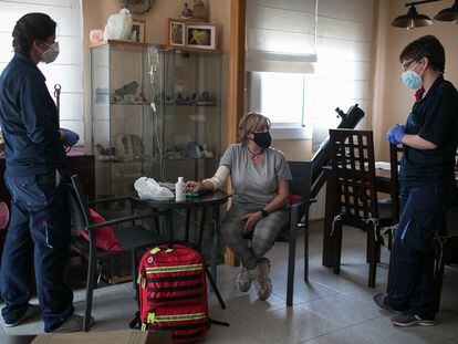 Mónica, una paciente del hospital Moisès Broggi, es atendida por dos sanitarias en su domicilio.