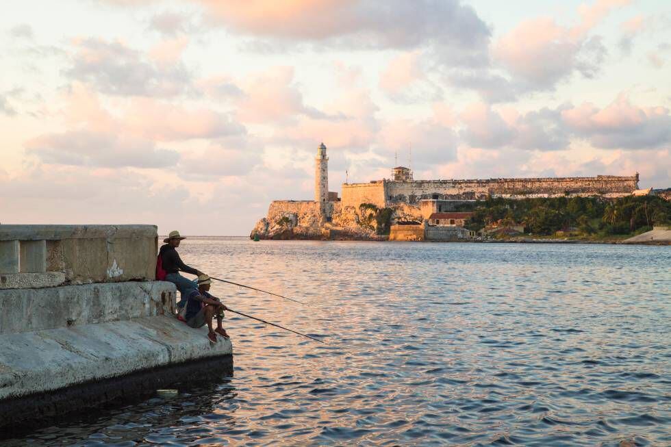 Un pescador en el Malecón de La Habana con el castillo de los Tres Reyes del Morro al fondo.