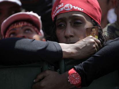 Una chavista sujeta un recordatorio de Ch&aacute;vez mientras espera el paso del cortejo funerario hacia una academia militar en Caracas. 