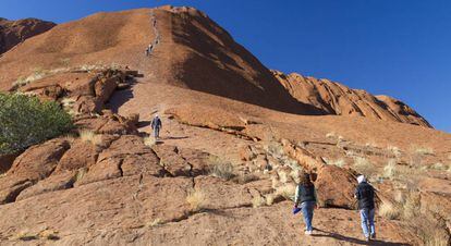 Un grupo de turistas escalando la roca Uluru.