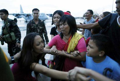 Varios supervivientes se agarran a sus familiares mientras son obligados a subirse a un avión militar que los trasladará a Manila en el aeropuerto de Tacloban.