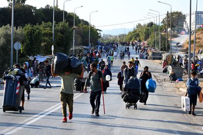 Migrantes del campo incendiado de Moria caminan hacia una nueva ubicación en la isla griega de Lesbos, el jueves.