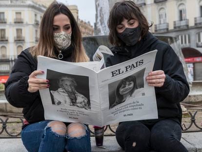 Dos jóvenes leen EL PAÍS en un banco en Madrid.