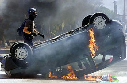 <font size="2"><b>La policía italiana irrumpe en el cuartel general del Foro Social de Génova</b>/a></font><p>Un activista cruza tras un coche en llamas en los enfrentamientos de ayer (AP).<br>- <font size="1"><b>Galería</b>: <a href=http://www.elpais.es/fotografia/especiales/secuencia/1.html>Muerte de un manifestante en Génova</font></a>