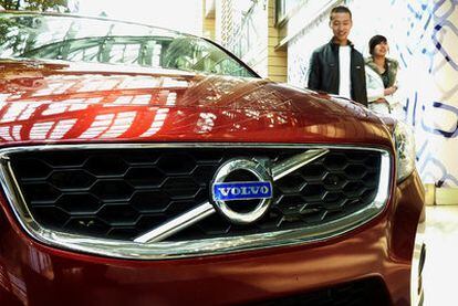 Dos ciudadanos chinos pasan delante de un coche marca Volvo en un centro comercial de Pekín.