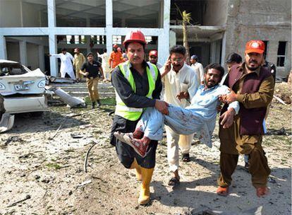 Dos personas transportan a un hombre herido por el atentado en Peshawar.