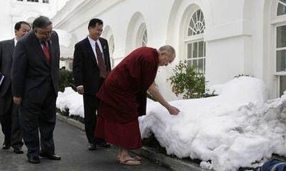 El líder tibetano toca la nieve mientras se dirige a reunirse con el presidente Barack Obama hoy en la Casa Blanca