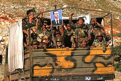 Soldados sirios portan retratos del presidente Bachar el Asad en el camión en el que se replegaron ayer a su país.