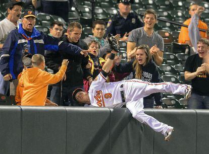 Nate McLouth, de Baltimore Orioles recupera la pelota de forma acrobática durante un partido de béisbol.