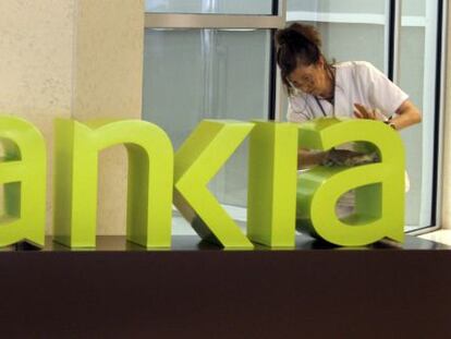 Una operaria limpia el logo de Bankia. 