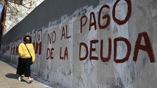 Una mujer pasa frente a una pintada contra el pago de la deuda, en Buenos Aires.