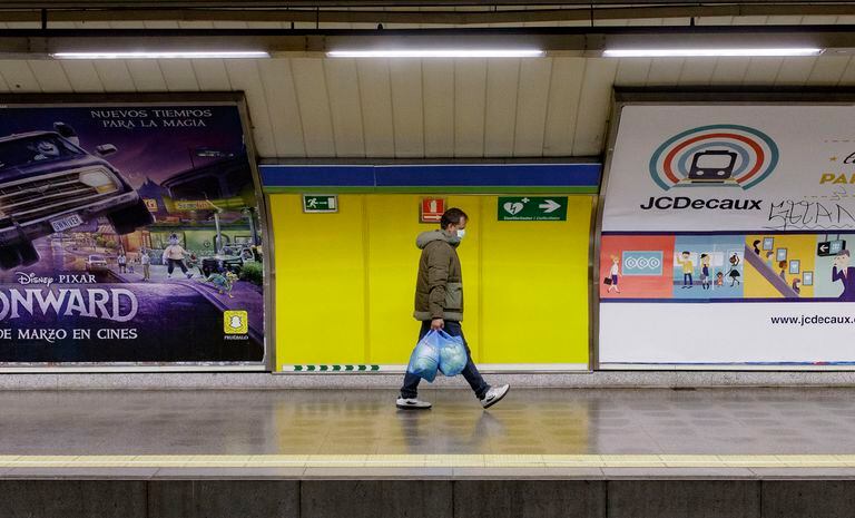 Un hombre protegido con mascarilla camina por un andén vacío del metro de Madrid.
