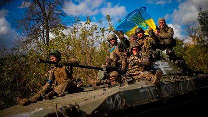 Soldados ucranios enarbolan la bandera nacional mientras viajan en un vehículo armado desde Izium a Liman.