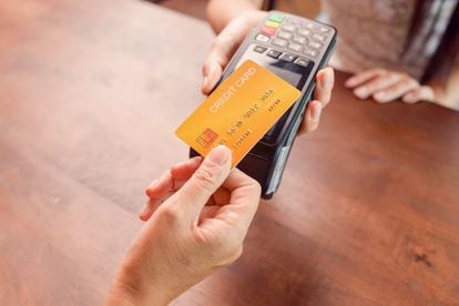 Una persona pagando con tarjeta de crédito en un comercio.
