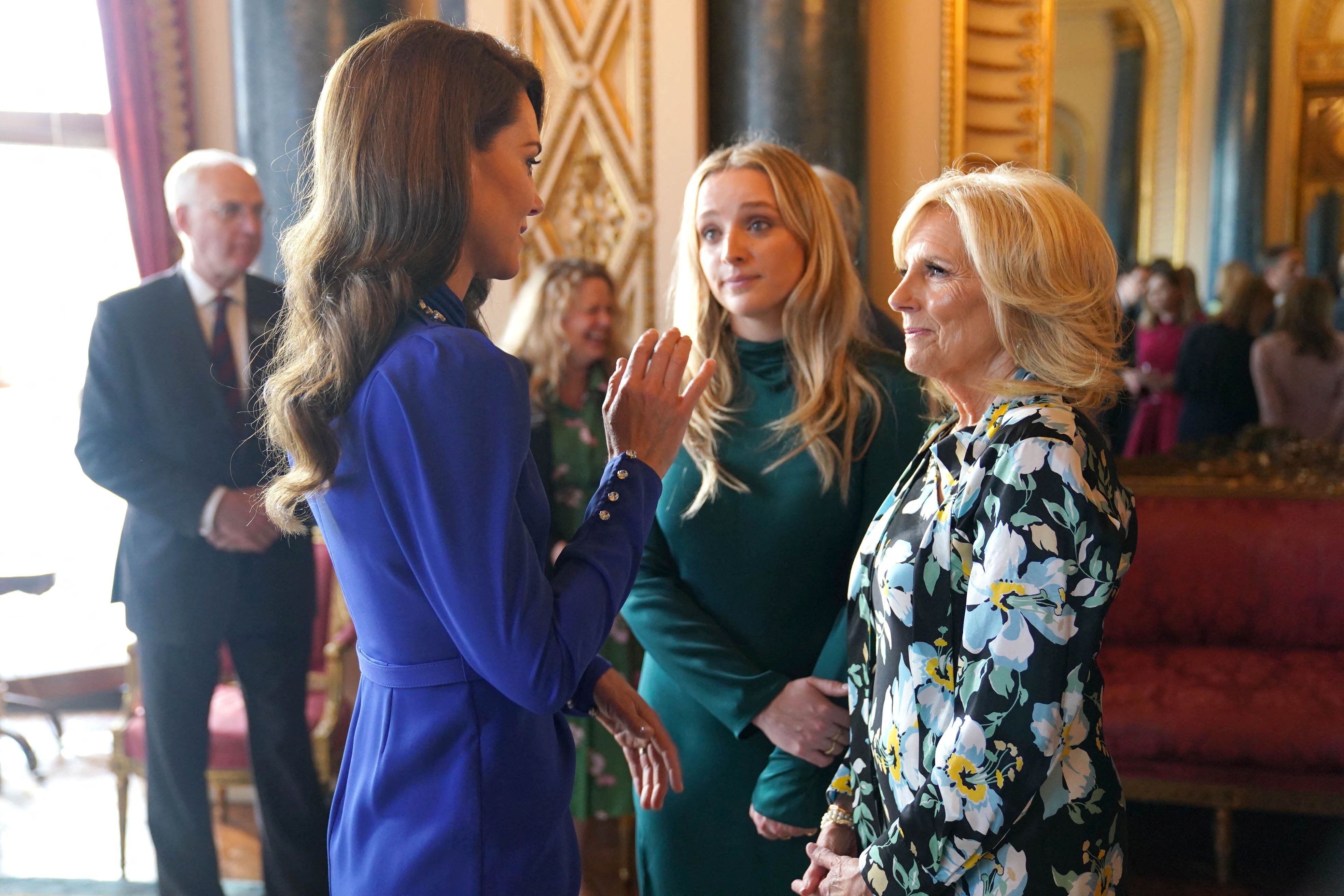 La princesa de Gales charla con la primera dama estadounidense Jill Biden y la nieta de esta, Finnegan Biden,  en uno de los salones de Buckingham.