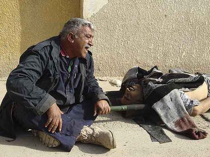 Un hombre llora cerca del cadáver de su hermano, muerto al estallar una bomba.