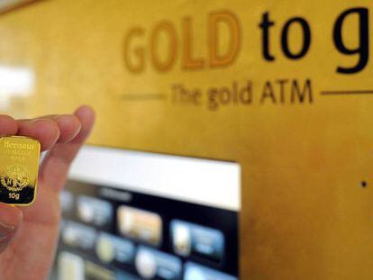 Un hombre sostiene una barra de oro de 10 gramos, despúes de la demostración de cómo se usa la máquina de venta de oro (