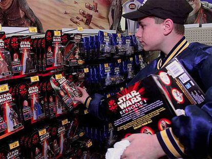 Un joven coloca juguetes de la saga &#39;Star Wars&#39; en una tienda estadounidense.