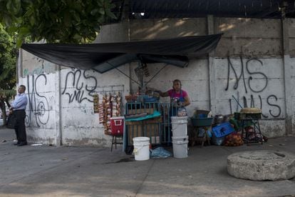 Una mujer vende comida en el parque infantil de San Salvador rodeada de pintadas de la Mara Salvatrucha. Las maras marcan su territorio con sus insignias, las cuales se pueden ver por toda la ciudad