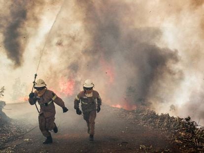 Dos bomberos se alejan de un incendio en Portugal el pasado junio.