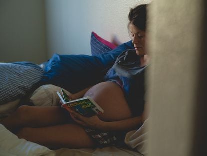 Una mujer embarazada lee un cuento en la cama.