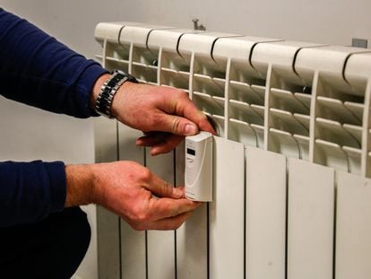 Un técnico instala un contador individual en un radiador de una vivienda en Madrid.