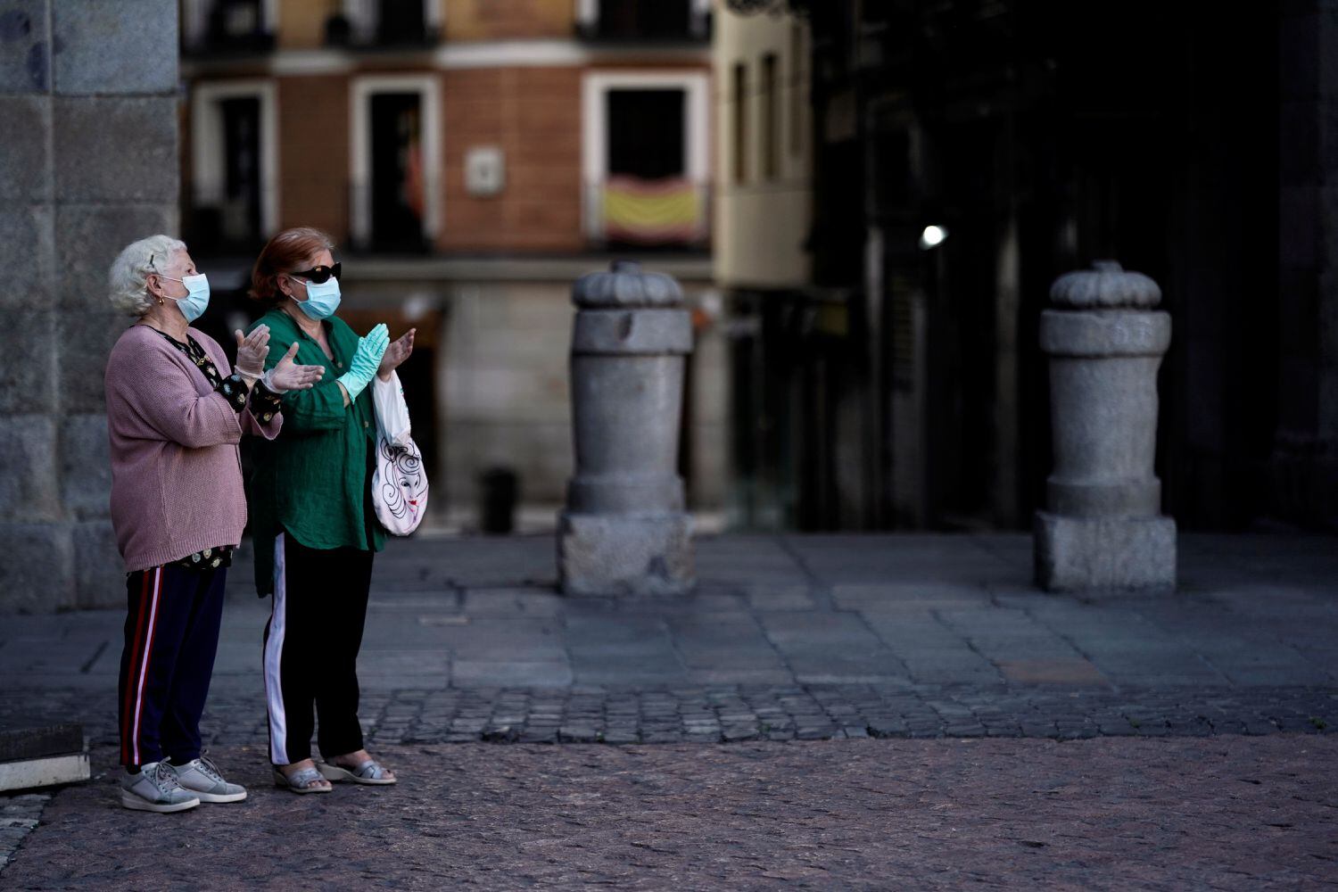 Dos mujeres, en la Plaza Mayor de Madrid, aplauden en homenaje al personal sanitario el 3 de mayo.