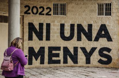 Una mujer pasa por delante de una pared donde se puede leer "Ni una menos" en un acto en memoria de las víctimas de violencia de género y sus hijas e hijos, en el antiguo cauce del Turia, el pasado 8 de marzo en Valencia.