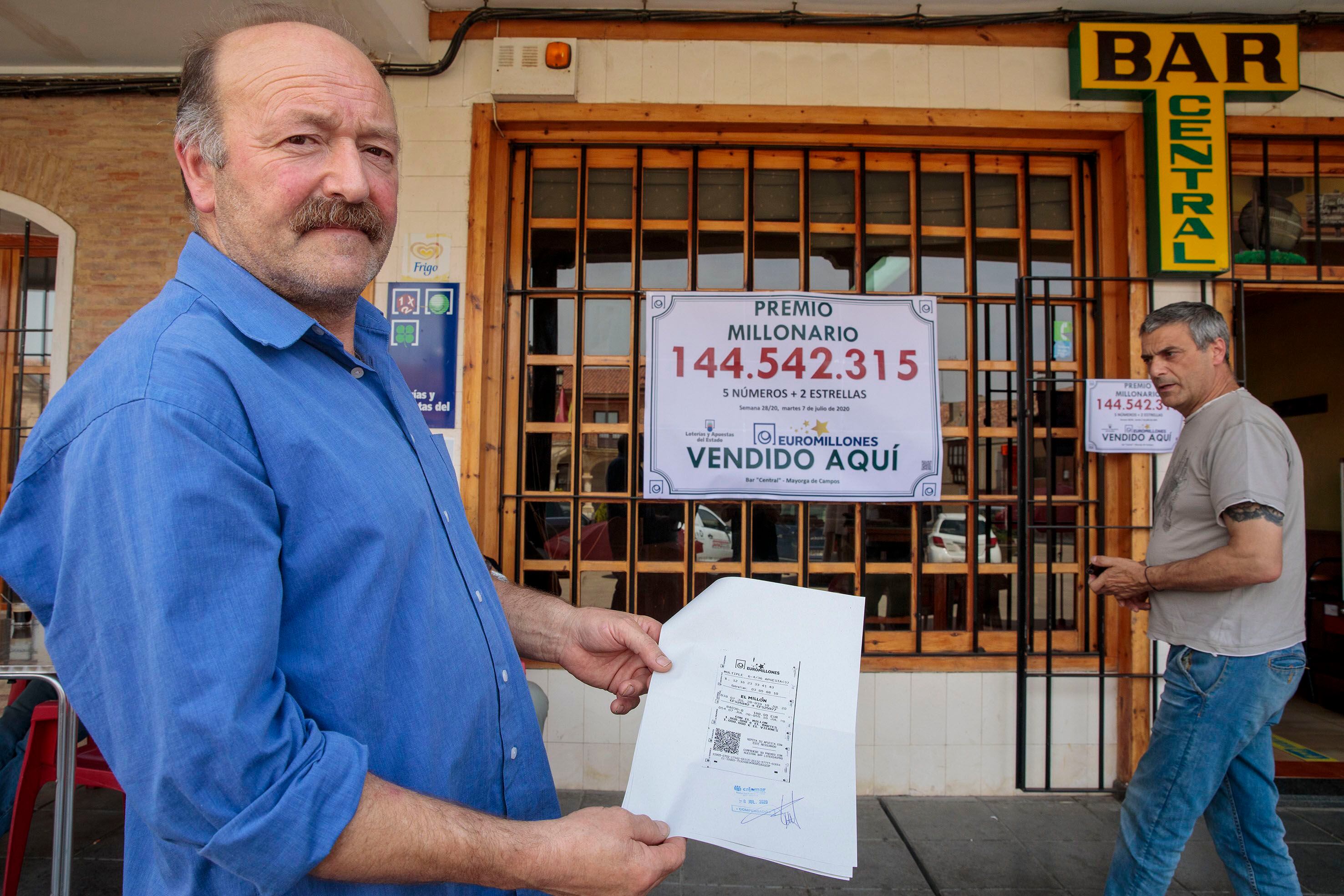 Ángel Iluminado Alonso muestra el boleto millonario ante su bar en Mayorga de Campos (Valladolid). 
