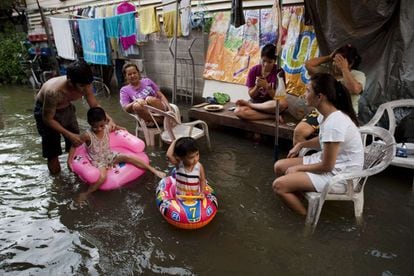 Una familia sentada fuera de su casa, cerca del río Chao Praya river en Bangkok