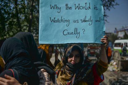 Una afgana sostiene un cartel en el que se lee "¿Por qué el mundo nos está mirando en silencio y cruelmente?"