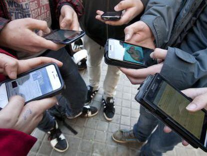 Varios menores se conectan a las redes sociales a través de sus teléfonos móviles.