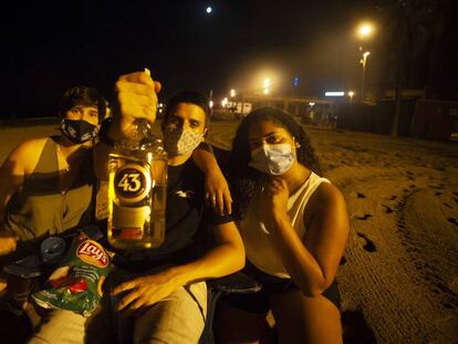 Joves fent un 'botellón' a la platja de la Barceloneta, divendres a la nit.