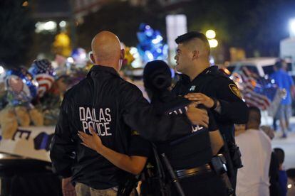 Dallas police officers comfort each other in front of police cars decorated as a public memorial Friday, July 8, 2016, in Dallas in front of police headquarters, in honor of police who were killed Thursday in shootings. (AP Photo/Gerald Herbert)