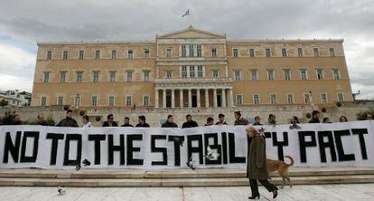 Activistas sostienen una gran pancarta en la que se lee "no al pacto de estabilidad" delante del Parlamento griego en Atenas.