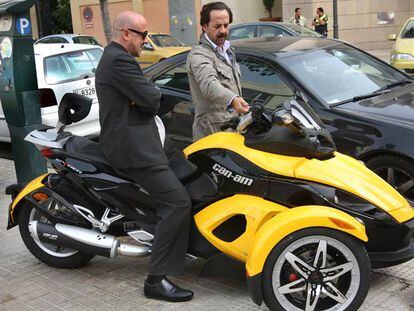 Álvaro Pérez (derecha) enseña su moto a un amigo frente a la sede del PP de Valencia.