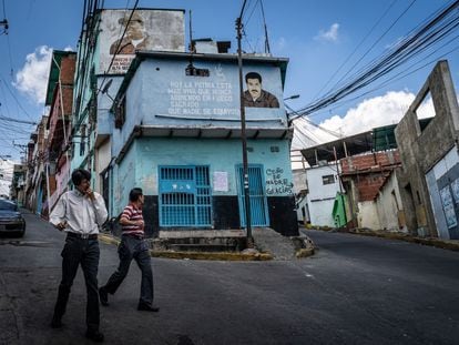 Peatones caminan frente a un mural de Nicolás Maduro en el barrio de Petare, en Caracas, en 2019.