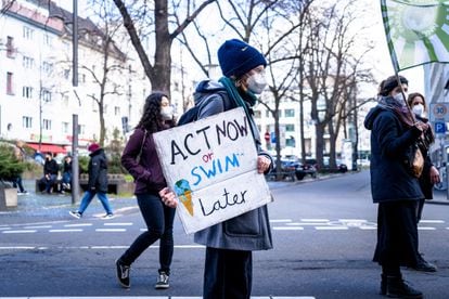 Un manifestante participa en una concentración por el clima, con una pancarta que dice "Actúa ahora o nada después".