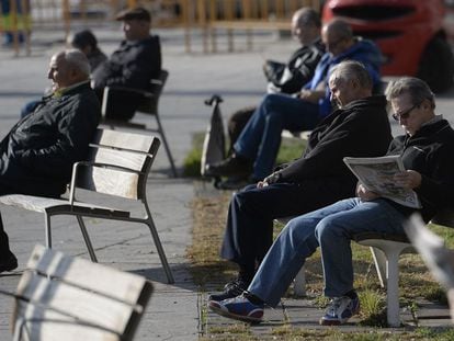 Un grupo de pensionistas toman el sol en un banco de una calle de Barcelona.