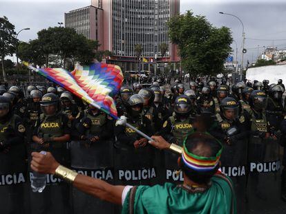 Un hombre ondea una bandera wiphala de los pueblos indígenas frente a miembros de la Policía, durante una marcha antigubernamental el 20 de enero de 2023.