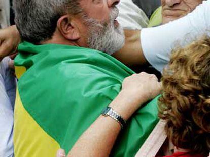 Lula, envuelto en una bandera de Brasil, saluda a sus seguidores  tras depositar su voto.