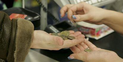 Una cajera ayuda a un cliente a contar las monedas.