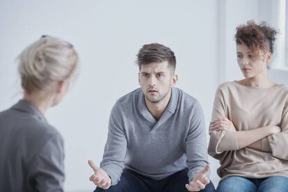 Una persona neutral escucha con atención a una pareja en una sesión de mediación.