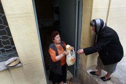 Una mujer reparte pequeñas cantidades comida a una anciana en Atenas