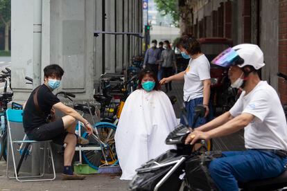 Shanghái ve desde este miércoles la luz al final del túnel, después de un estricto confinamiento de dos meses, que ha generado un amplio descontento entre la población. En la imagen, una mujer se corta el pelo en una calle de la ciudad, este miércoles. 