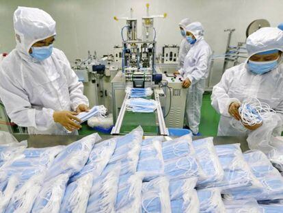 Trabajadores chinos empaquetan máscaras la pasada semana en una fábrica de Suining, en el suroeste del país. En vídeo, declaraciones del director de la OMS, Tedros Adhanom Ghebreyesus.
