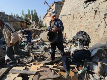 Tres hombres retiran escombros de sus casas tras un bombardeo en la regi&oacute;n de Donetsk.